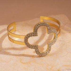 Dettaglio del bracciale dorato a doppio strato con un quadrifoglio scintillante di diamanti