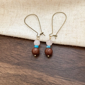 Detail of vintage bohemian earrings with pink stone and blue agate beads on linen fabric