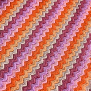Macro shot of colorful chevron knit fabric with orange, purple, and brown wavy patterns