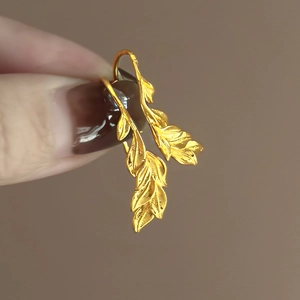 Close-up of 18k gold plated leaf earrings showing intricate metal textures and veins