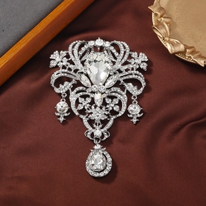 Vintage silver hollow brooch with crystals and teardrop pendants on silk background