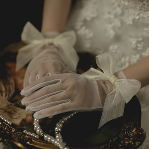 Detail shot of white mesh bridal gloves featuring a large decorative tulle bow