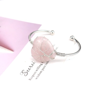Detail of pink crystal heart stone with silver wire tree of life wrapping on a bangle