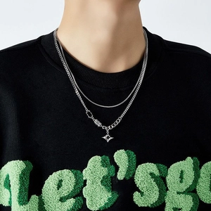 Detailed close-up of a silver double-layer necklace with a stylish cross pendant on a model