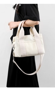 Detail of cream canvas tote bag featuring detachable strap and silver metal hardware