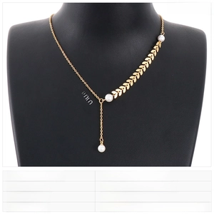 Macro detail of gold stainless steel wheat ear necklace with pearl on black display bust