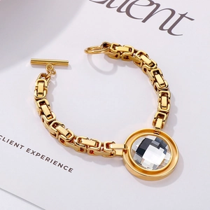 Detail shot of golden chunky chain bracelet featuring a large clear faceted crystal charm
