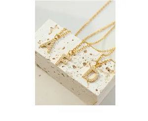 Detail of gold zircon initial necklaces A, F, D on stone for a luxury fashion look