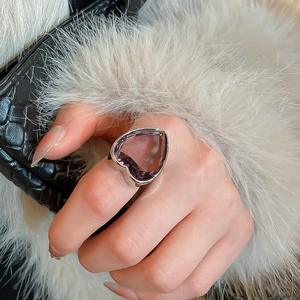 Detail showing an exaggerated heart-shaped purple zircon ring worn on a finger