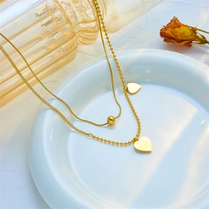 French vintage double-layered gold necklace with heart shell pendants on white ceramic plate