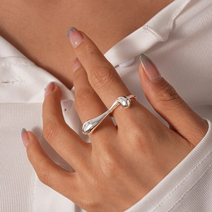 Detailed view of an irregular liquid metal silver ring worn on a finger for a minimalist look