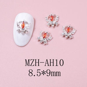 Macro shot of silver heart crown nail charms with red marquise stones and white rhinestones