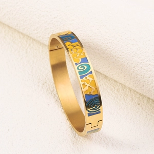 Macro shot of gold-plated bangle with yellow and blue enamel swirls on beige background