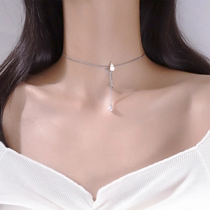 Macro shot of silver choker with hollow butterfly pendant and dangling white pearl tassel