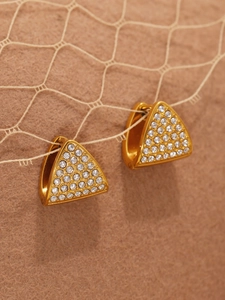 Macro shot of triangle gold earrings with pavé zircons on a lace background
