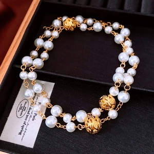 Close-up of double-layer pearl necklace with golden floral beads on black velvet