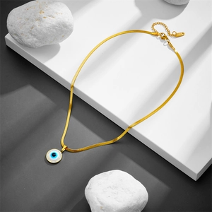Gold evil eye pendant necklace with snake chain on modern geometric display stand