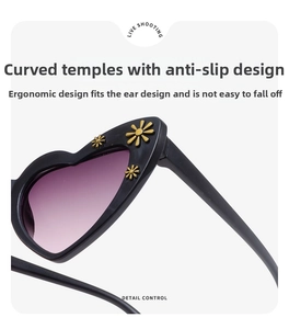 Detail of heart-shaped sunglasses with golden flower decor and curved non-slip temples