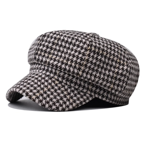 Detail of vintage houndstooth newsboy hat with golden silk thread and tweed texture