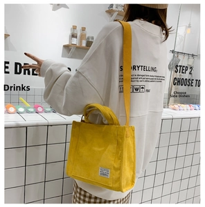 Detail of yellow corduroy small square bag with shoulder strap in a cafe setting