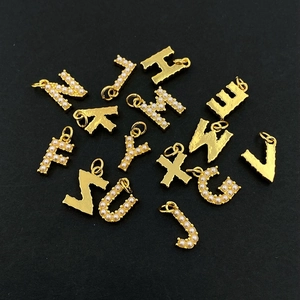 Minimalist gold necklace letter pendants with pearls and matte finish on black backdrop