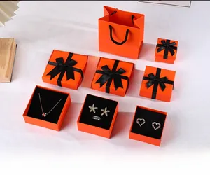 Macro view of orange jewelry gift boxes with black ribbons and velvet inserts for rings