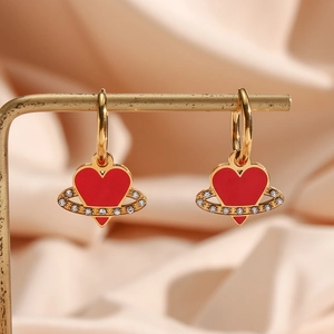 Golden hoop earrings with red heart enamel pendant and rhinestones on a metal stand
