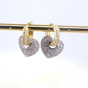 Macro shot of gold heart earrings with sparkling cubic zirconia on a minimalist white background
