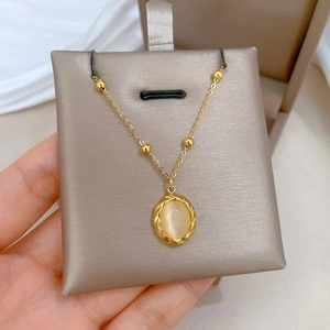 Gold titanium steel necklace with an oval cat eye stone pendant on champagne velvet