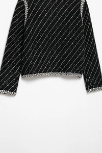 Detail of black knit cardigan with white diagonal stripes and contrast trim design