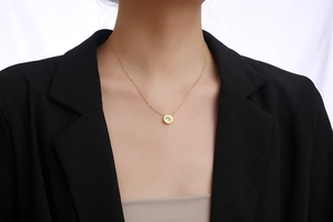 Close-up of elegant gold necklace with a round zircon pendant worn with a black blazer