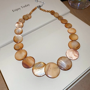 Detailed close-up of natural shell beads with warm brown texture and silver lobster clasp