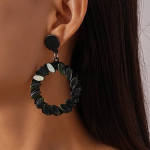 Close-up of geometric hollow round earrings in dark acrylic worn by a fashion model