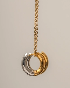 Close-up of intertwined gold and silver C-shaped rings on a polished metal necklace