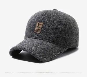 Close-up of dark grey newsboy cap with herringbone pattern and brown leather patch detail