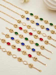 Detalle de pulseras de acero inoxidable dorado con dijes de cristal de varios colores