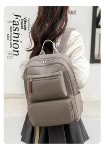 Detail of taupe casual backpack featuring multiple zipper compartments and padded straps
