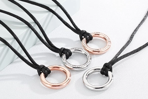 Detail of rose gold and silver circular pendants on black woven ropes with crystal accents