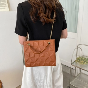 Chic brown quilted crossbody bag with golden chain strap on a fashion model