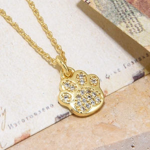 Macro shot of gold-plated paw print pendant necklace with shimmering cubic zirconia