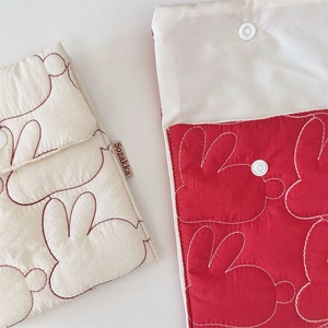 Detail of red and cream quilted sanitary pouch with rabbit pattern and resin snap button