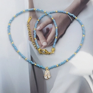 Close-up of sky blue crystal beaded necklace with golden flower pendant and lobster clasp