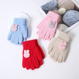 Detail of four pairs of thick knitted children's gloves in blue pink red and beige