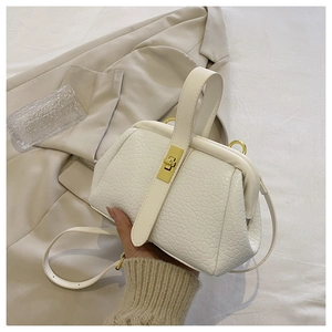 Elegant white crocodile pattern handbag with gold clasp on beige blazer background