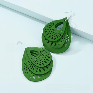 Close-up of green triple-layer hollow water drop earrings with intricate laser-cut patterns