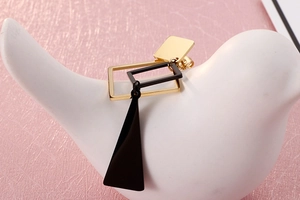 Detail of geometric asymmetric earrings with gold rectangle and black triangle on display