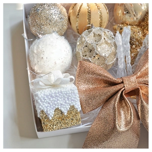 Close-up of champagne and gold glitter Christmas ornaments including bows and baubles