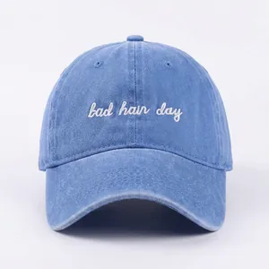 Détail de la broderie bad hair day blanche sur la casquette de baseball en jean délavé