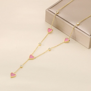 Detail of gold heart necklace with pink enamel and crystals over a jewelry box