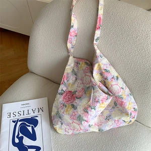 Detailed shot of floral canvas tote bag resting on a sofa with an art book